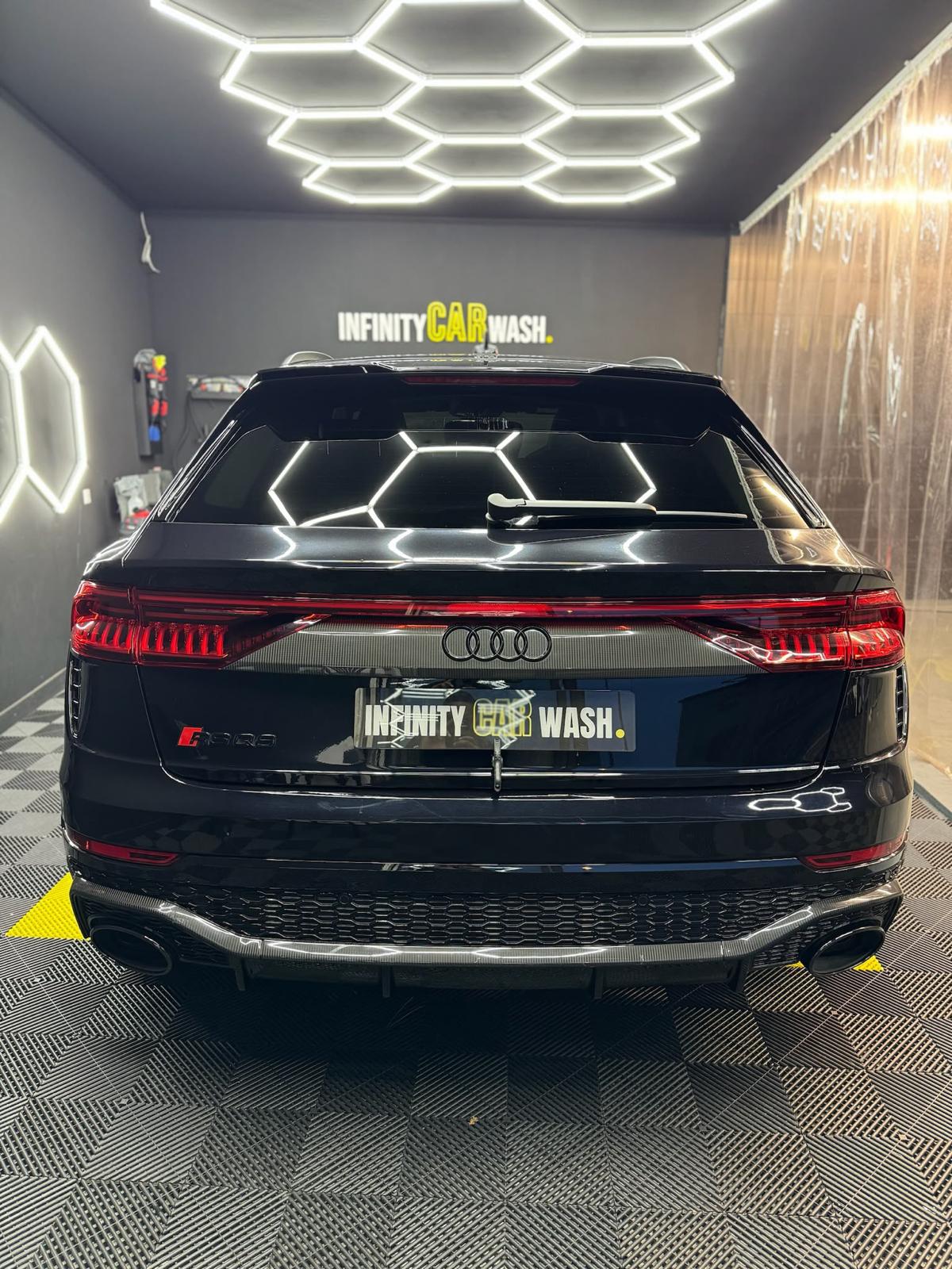 Audi RS Q8 noire à la finition miroir sous les néons hexagonaux